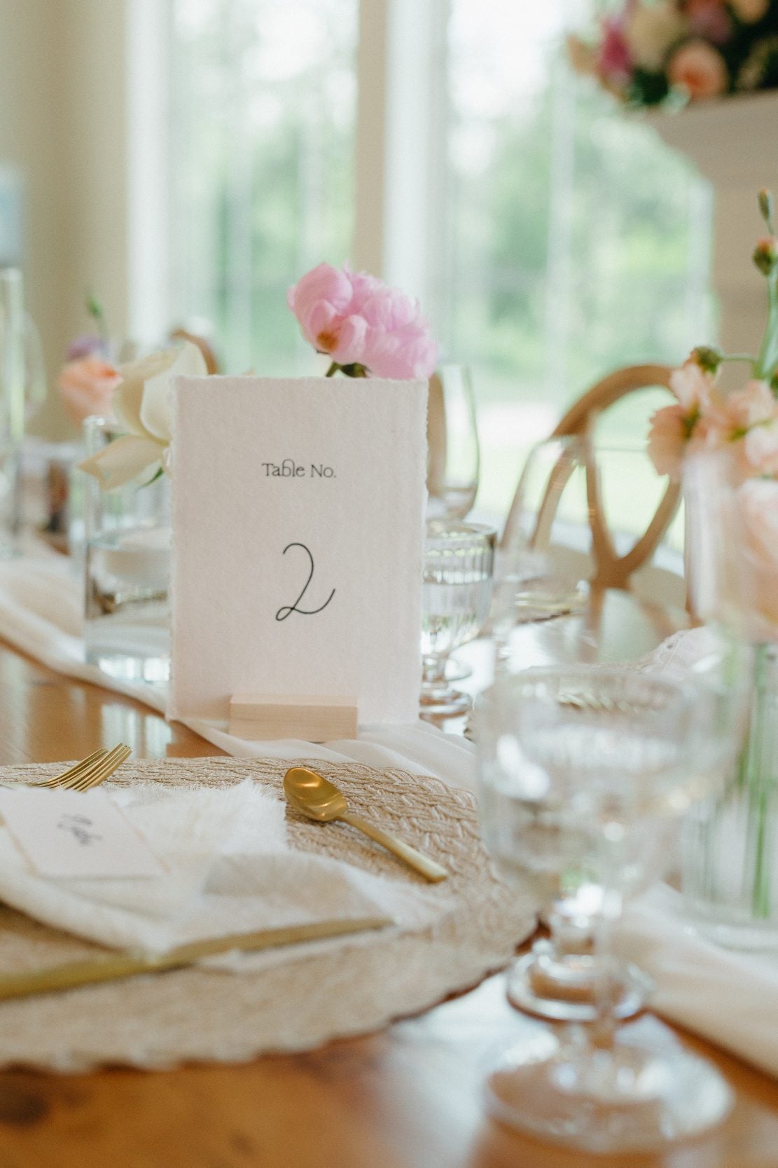 One of the guest tables with #2 table number, and several bud vases with mixed pastel blooms.
