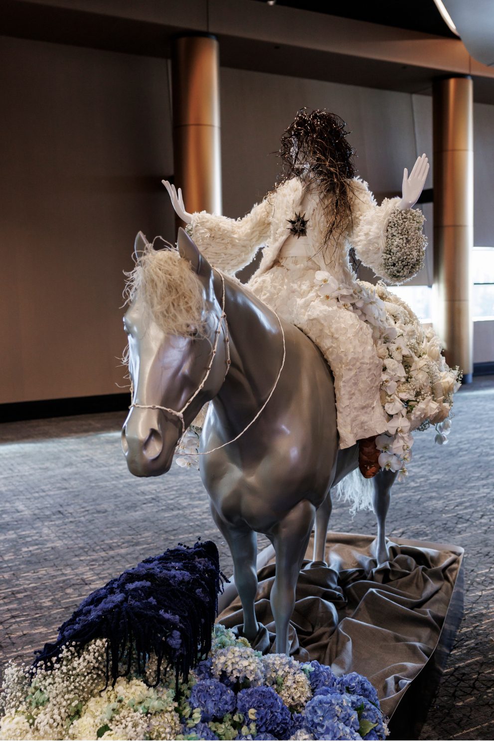 Floral mannequin of Shania Twain in a white floral jacket riding a silver horse at the Calgary Stampede Fleur de Villes event.
