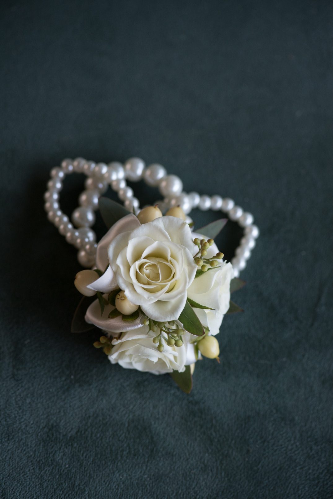 Bella Sprout Classic Blush Corsage A "Classic Blush" wrist corsage of ivory spray roses and eucalyptus on a pearl bracelet.