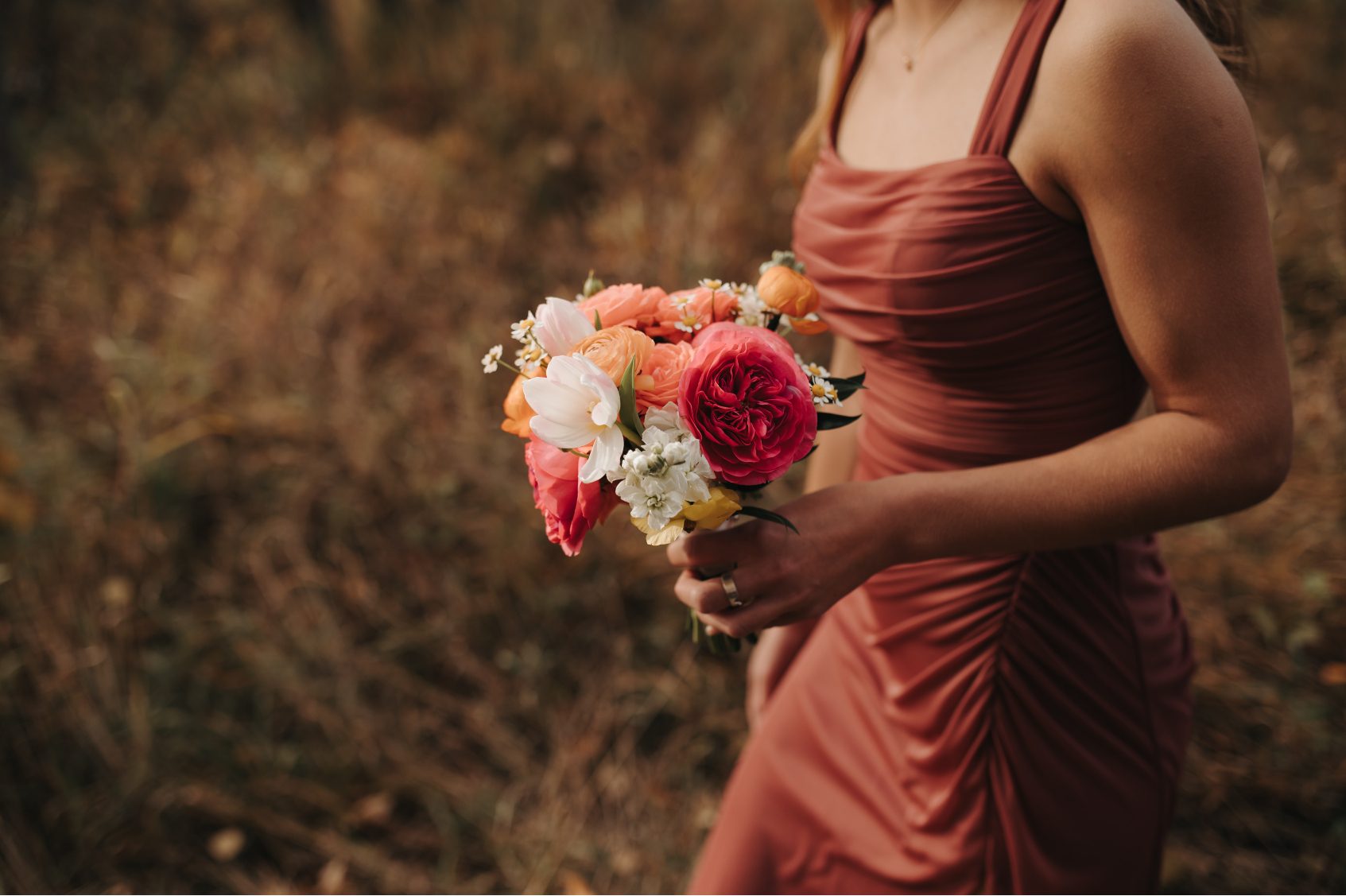 Bridesmaid in antique rose gown holding a bouquet of roses, tulips, ranunculus, stock and chamomile.