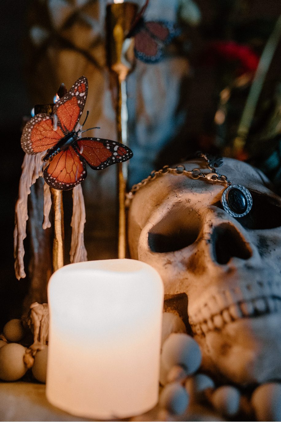 Elegant altar detail with butterflies, florals and a skill surrounded by candles and vibrant blooms.