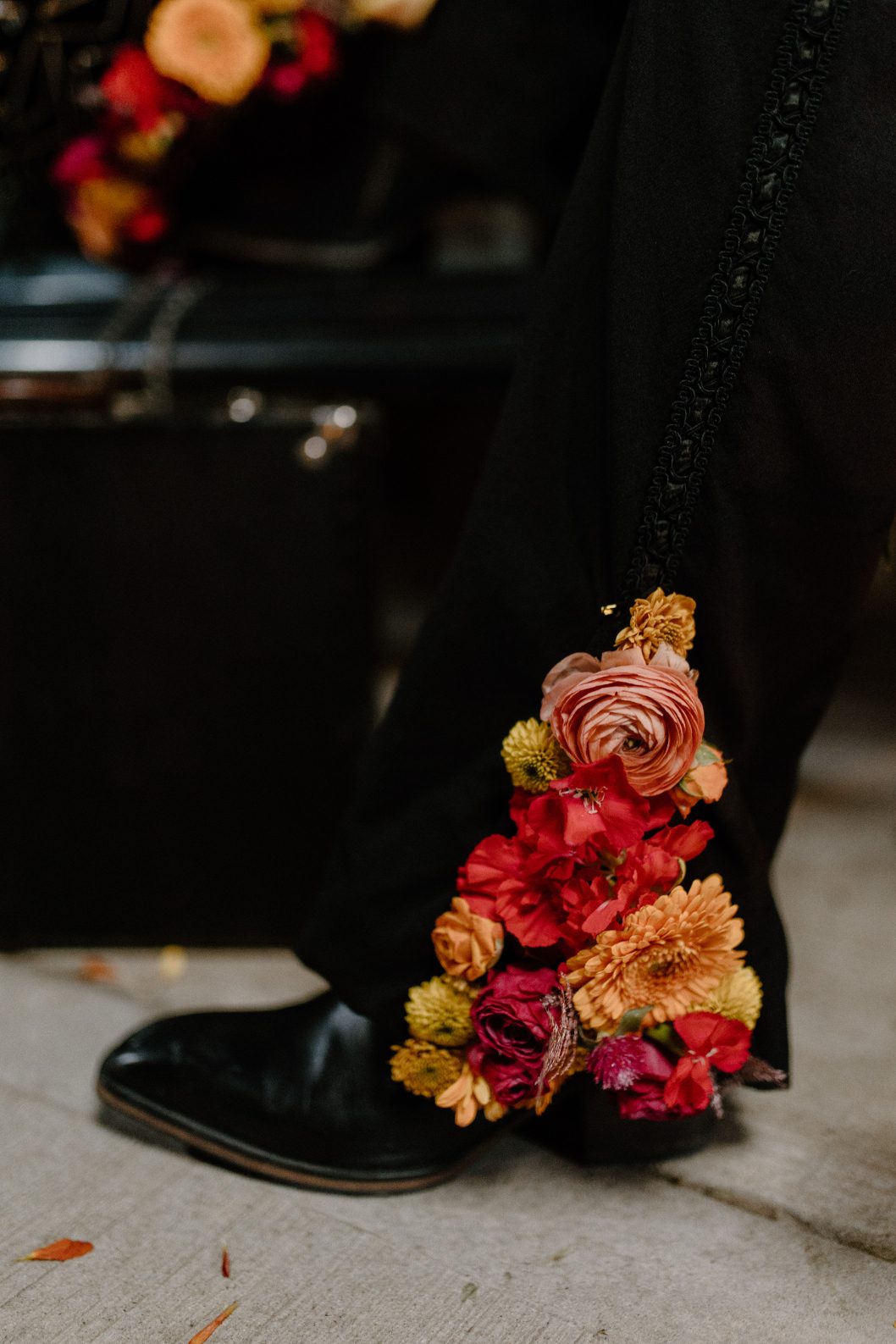 Floral detail on male model's pant leg featuring ranunculus, marigolds and red blooms for a bold, unexpected touch.
