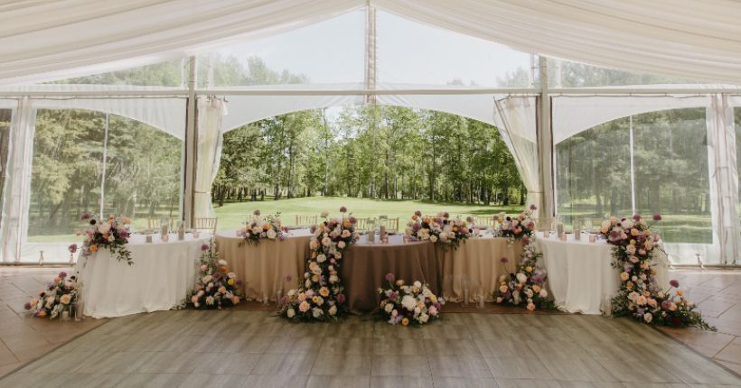 Stunning head table design at Hilltop with brown satin linens and beautiful arrangements displayed both on the table and the floor in front.