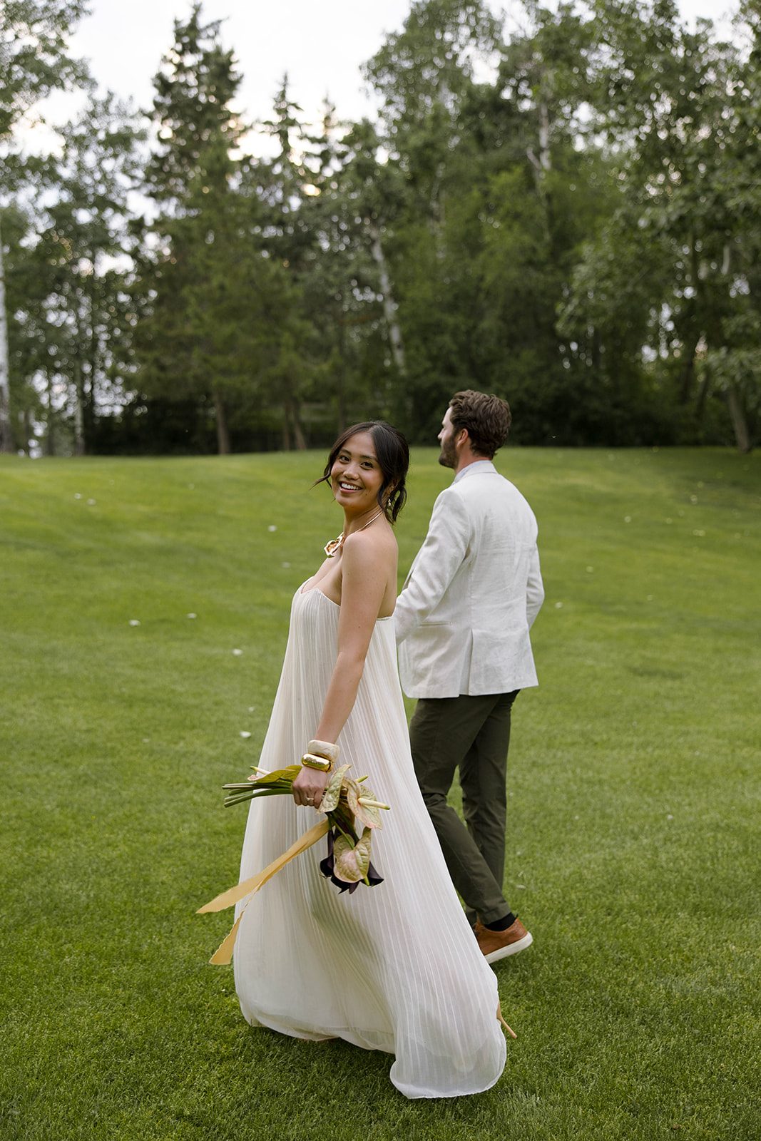 The bride and groom swap their outfits for more casual attire, walking the beautiful grounds of Hilltop hand in hand.