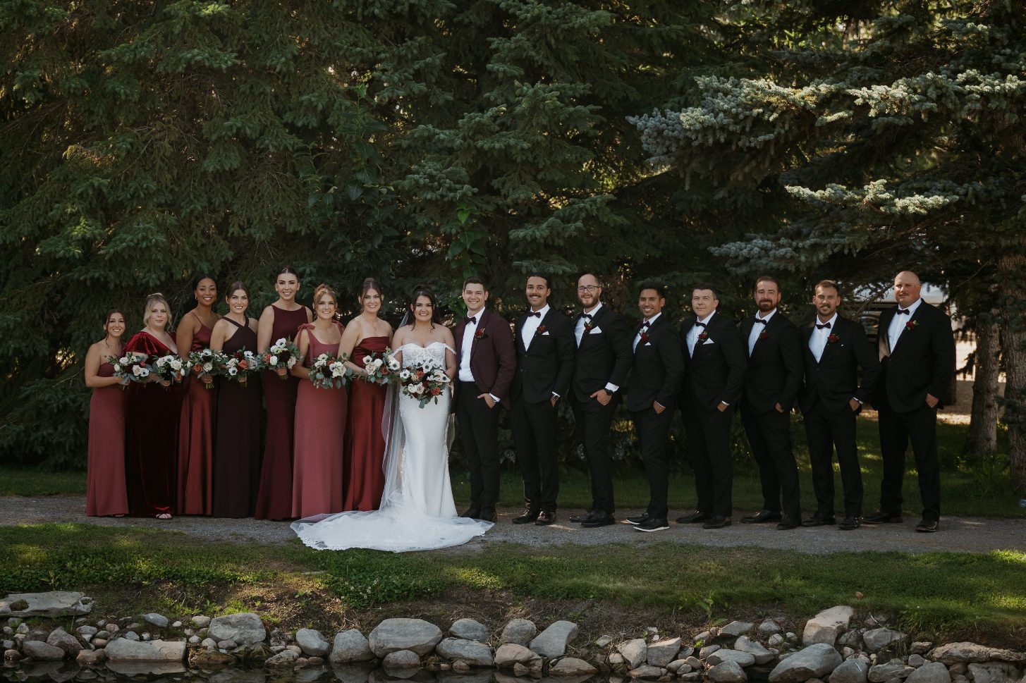 Bride, groom, bridesmaids and groomsmen gathered closely in a joyful group pose.