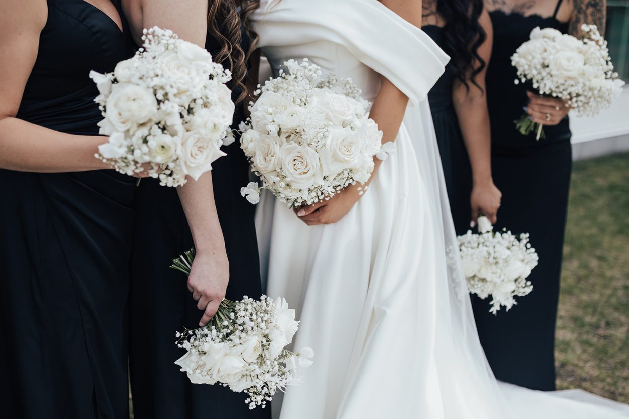 Bouquets Bride and bridesmaids holding matching white rose and baby's breath bouquets, captured from the shoulders down.