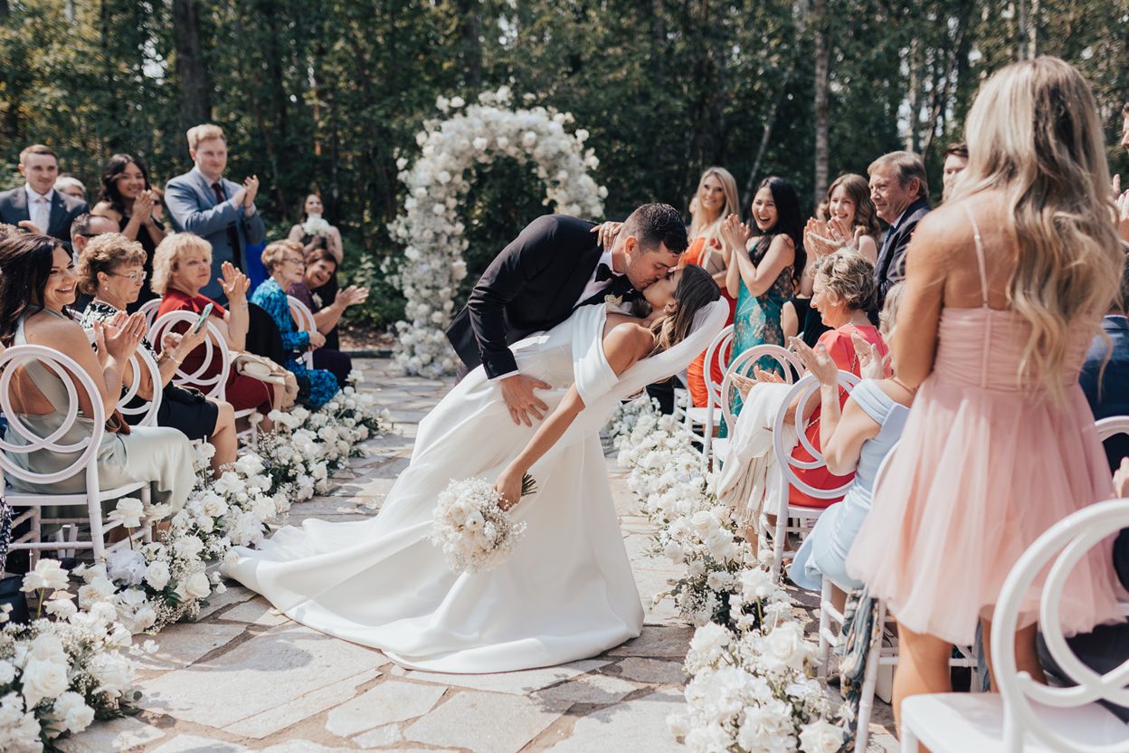 Dipped Groom dips the bride for a celebratory kiss part way down the aisle as guests applaud.