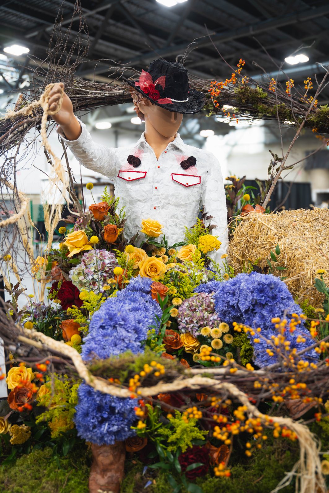Fleur de Ville event in Edmonton with a cowboy sitting down with his "lasso" of woven dried goods circling above his head.