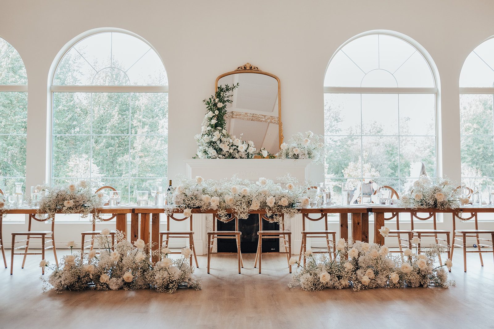 Mr + Mrs Day Panoramic view of the head table in front of a mantle, all adorned with fluffy arrangements of roses and baby's breath.