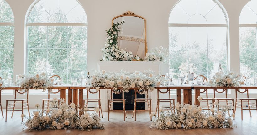 Feature Thin Beautiful head table set up at Sparrow Lane adorned with fluffy white arrangements full of baby's breath.