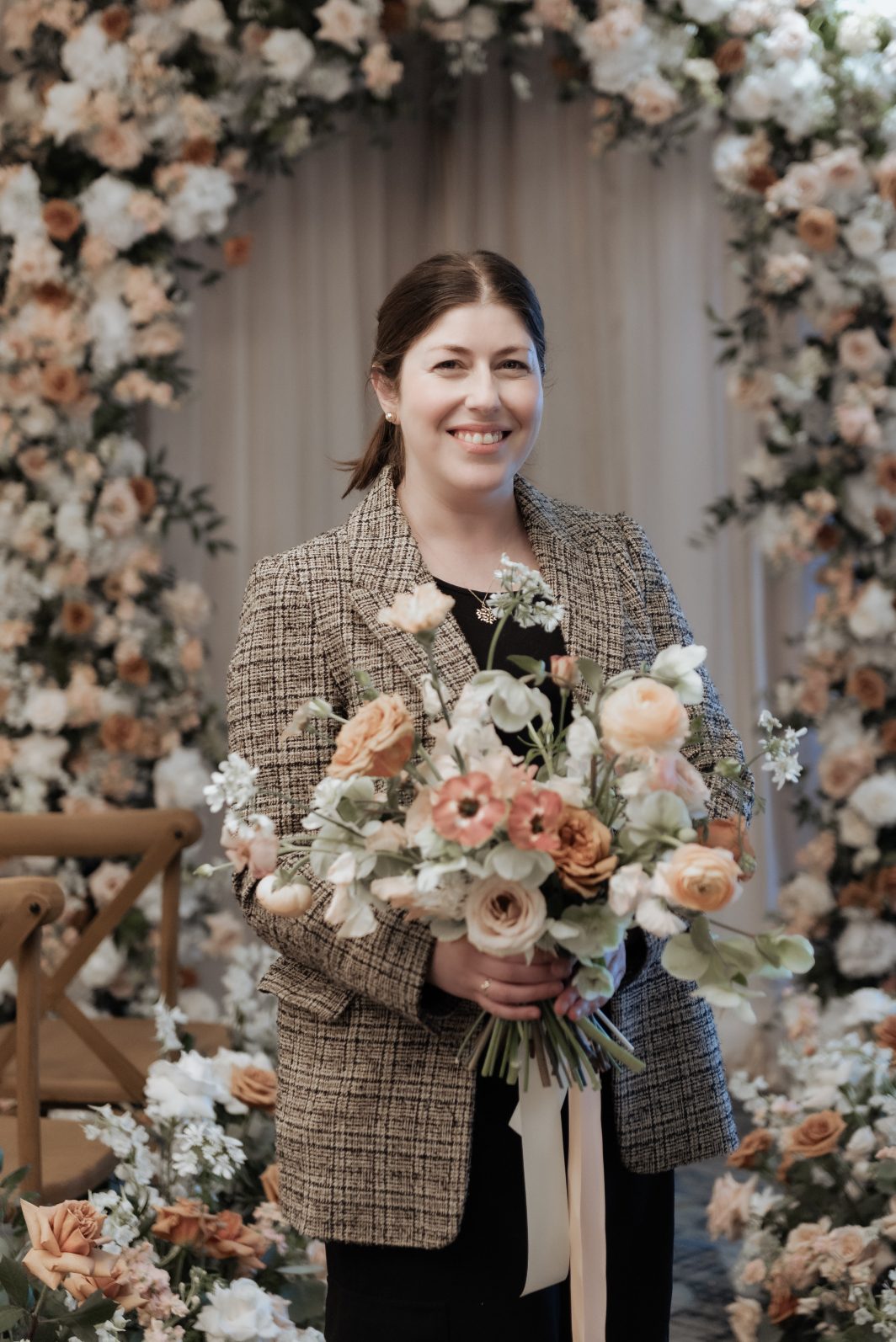 Our Calyx Team Member, Lucy, holding a beautiful bouquet of mixed whites and neutrals and smiling at the camera.