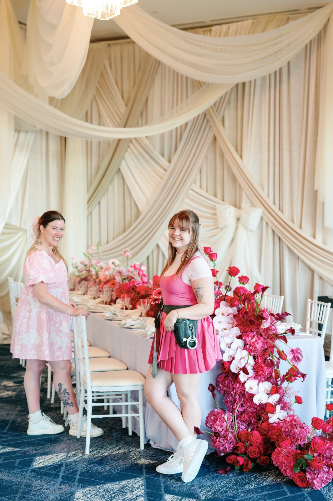 Travis and Erin in Orlando, both wearing pink and standing next to an ombre pink tablescape with a waterfall of dark pink flowers cascading down the front of the table.