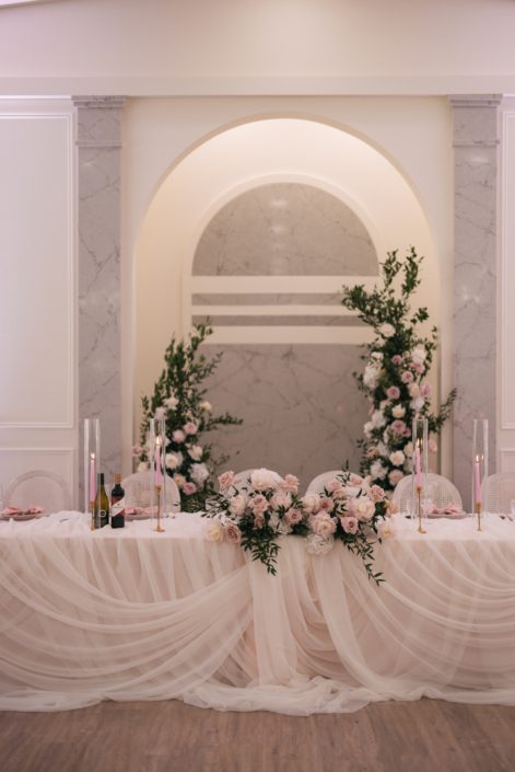 The head table inside Archway Manor features beautiful draping fabric for a very romantic feel, with a pretty blush and white centrepiece in the centre of the able, and the broken arch from their ceremony displayed behind the table.
