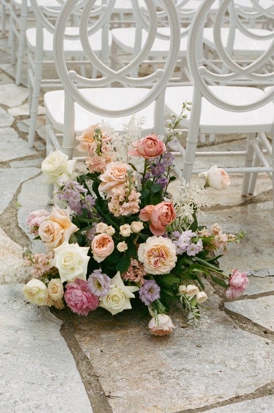Aisle Arrangements Arrangement at the start of the aisle containing peonies, roses, lisianthus, ranunculus and stock in pretty pastel tones.