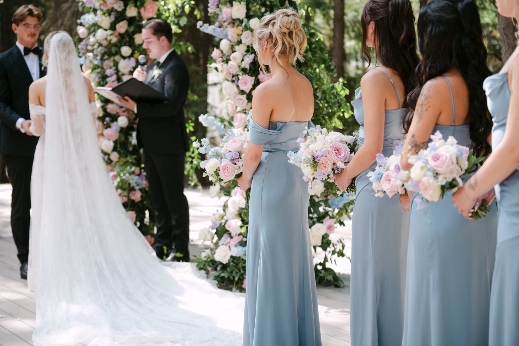 The view from behind Kaylee, with her bridesmaids lined up behind her and her groom gazing lovingly at her during the ceremony.