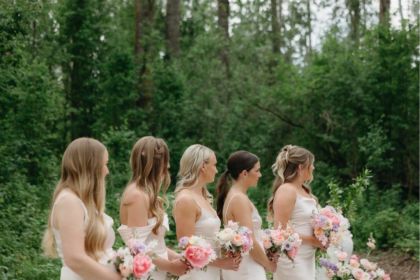 Bridesmaids + Bouquets Alyssa's bridesmaids all lined up during the ceremony holding pretty pink, peach and purple bouquets.