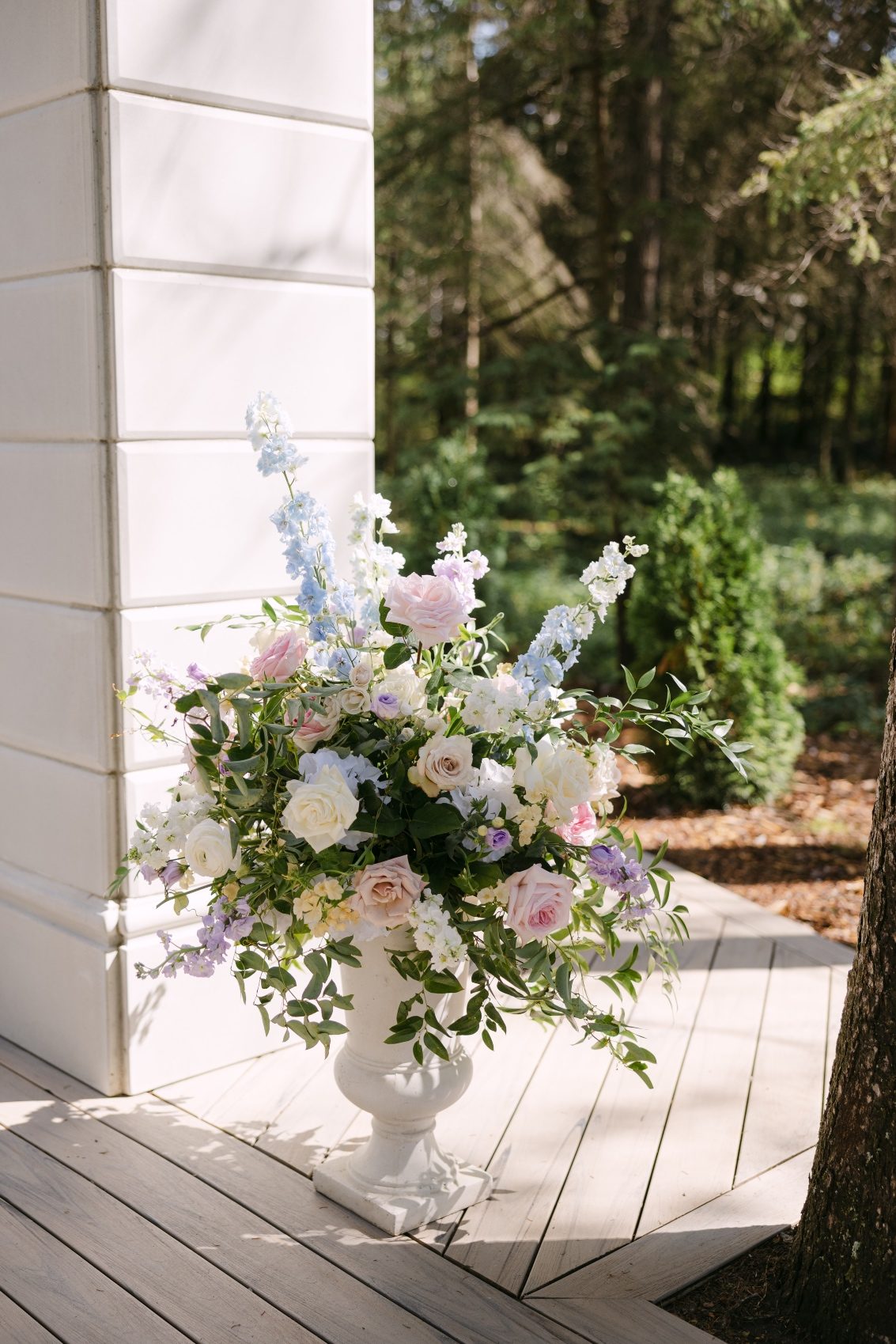 The other floral urn arrangement with the stone arch in behind.