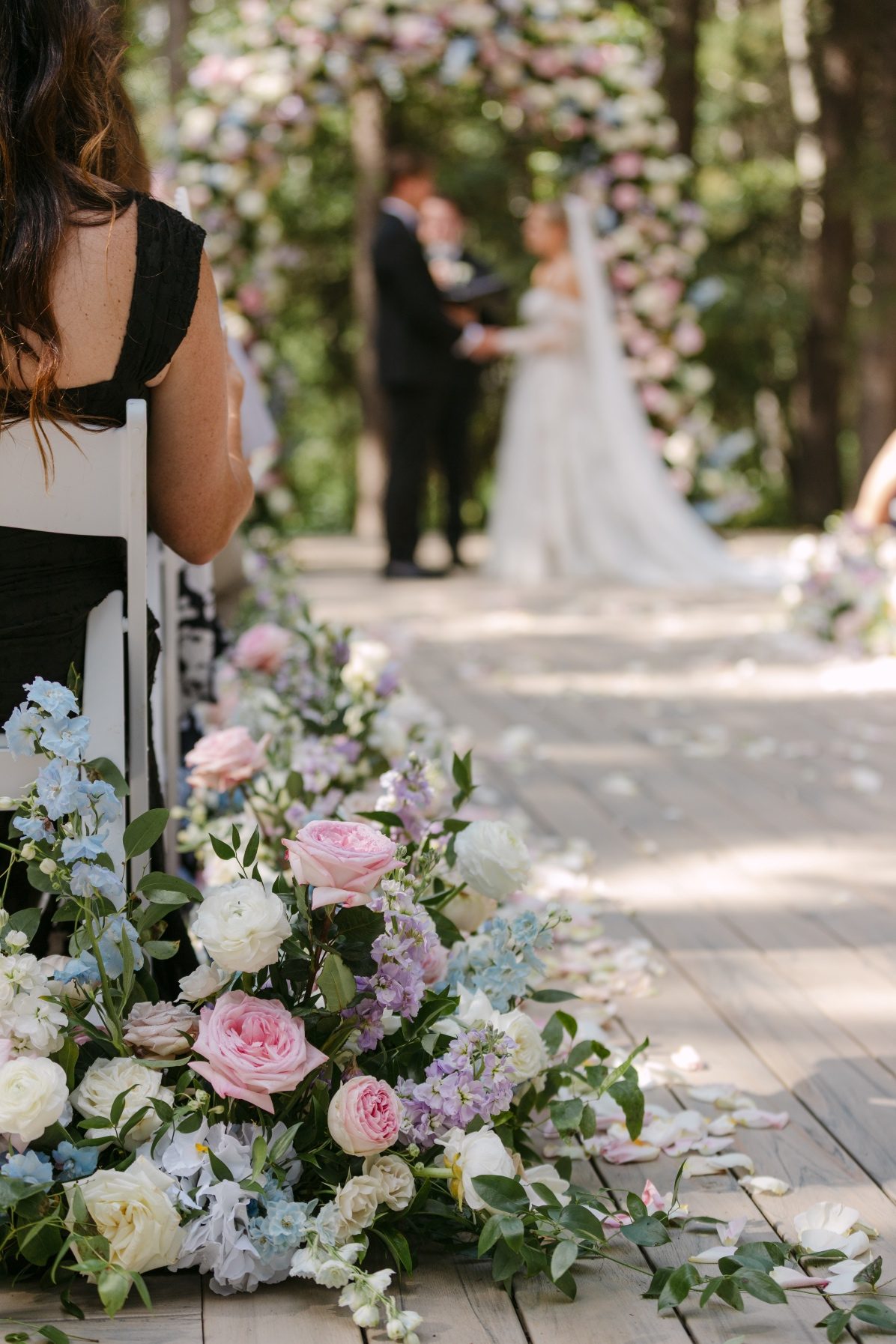 LNP1-2326 A close up of the aisle arrangements during the ceremony, with the couple standing in front of the arch gently blurred in the background.