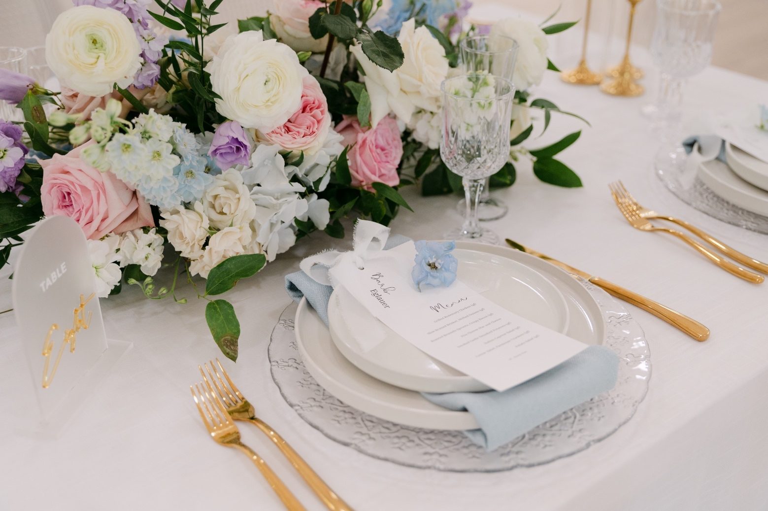 Beautiful pastel blooms from the centrepiece in front of a perfectly styled place setting for one of the wedding guests.