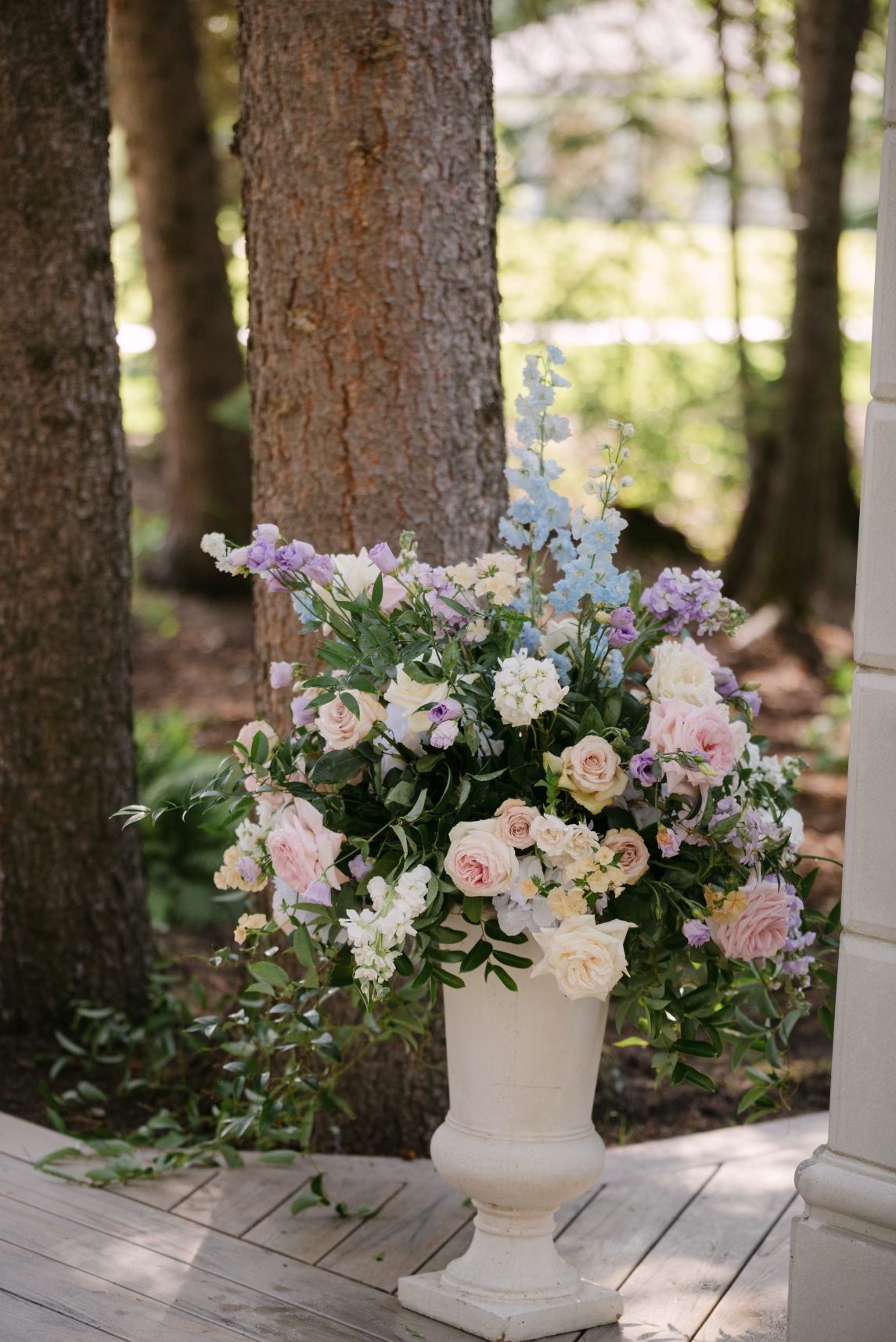 One of the gorgeous floral urn arrangements overflowing with delphinium, stock, lisianthus, roses, tweedia, lisianthus and lush greens.
