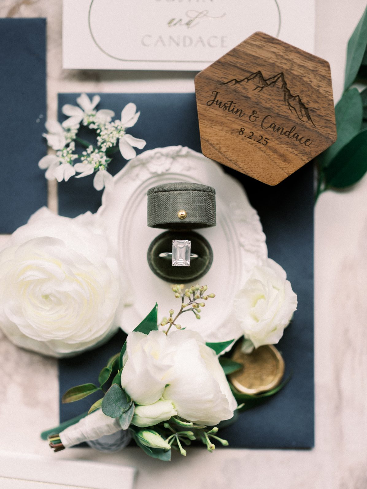 C&J Flatlay Wedding flat lay featuring emerald cut engagement ring, boutonnière and custom wooden wedding detail.