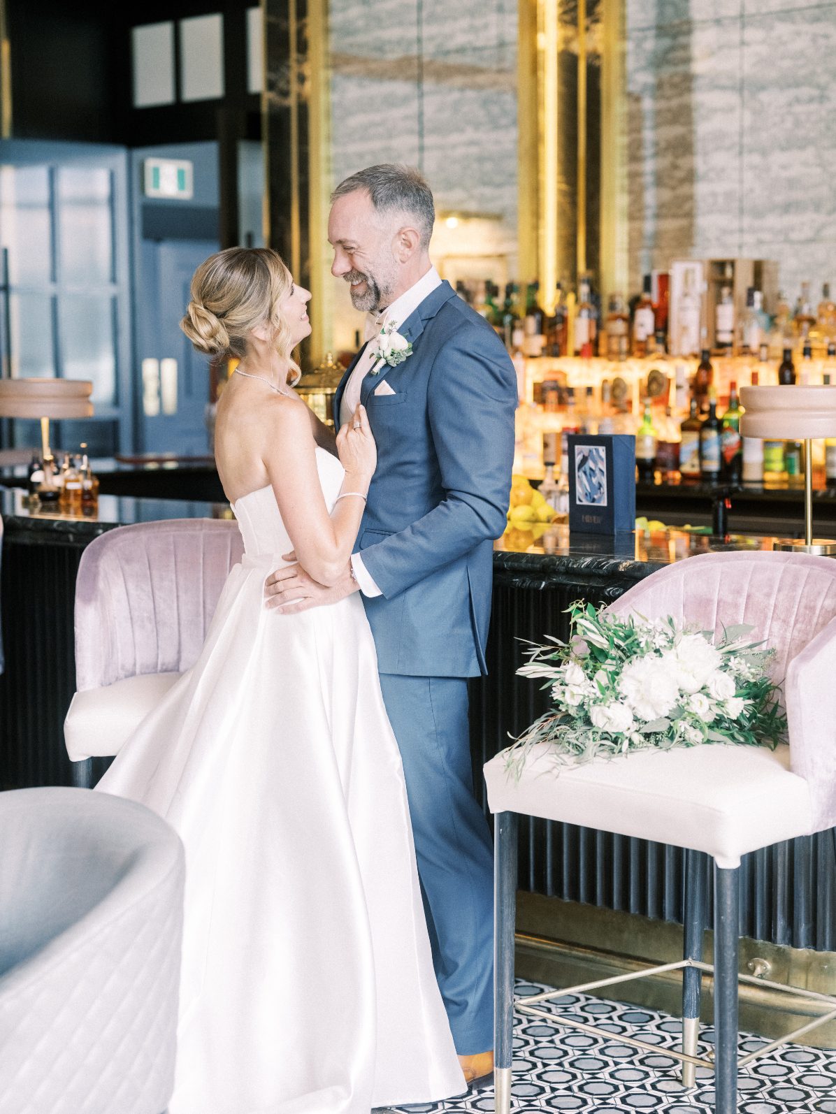 C&J Bride and groom sharing a romantic moment at a modern bar venue with soft wedding floral.