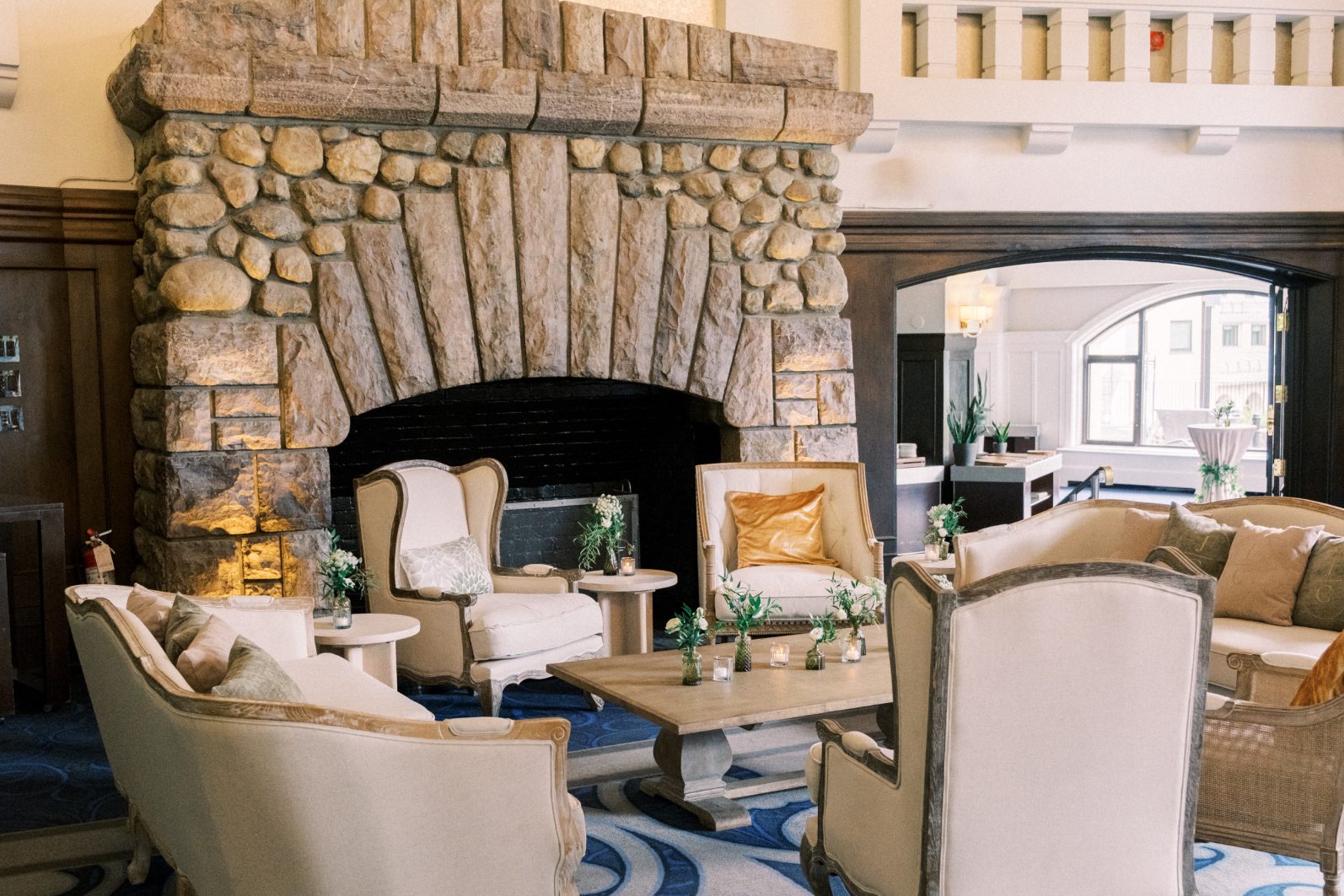 Cozy Seating Area Refined lounge vignette with stone fireplace, very seating and subtle floral accents creating a warm reception setting,