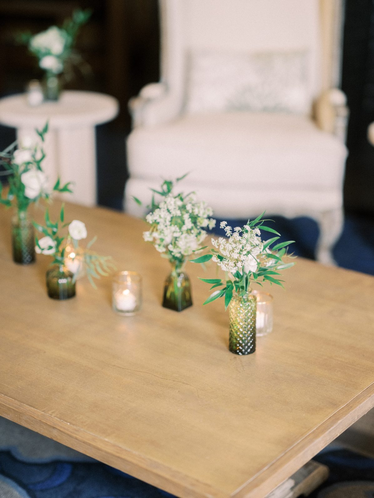 Dainty Budvases Close up of minimalist bud vases with delicate white blooms and candlelight on a wooden coffee table