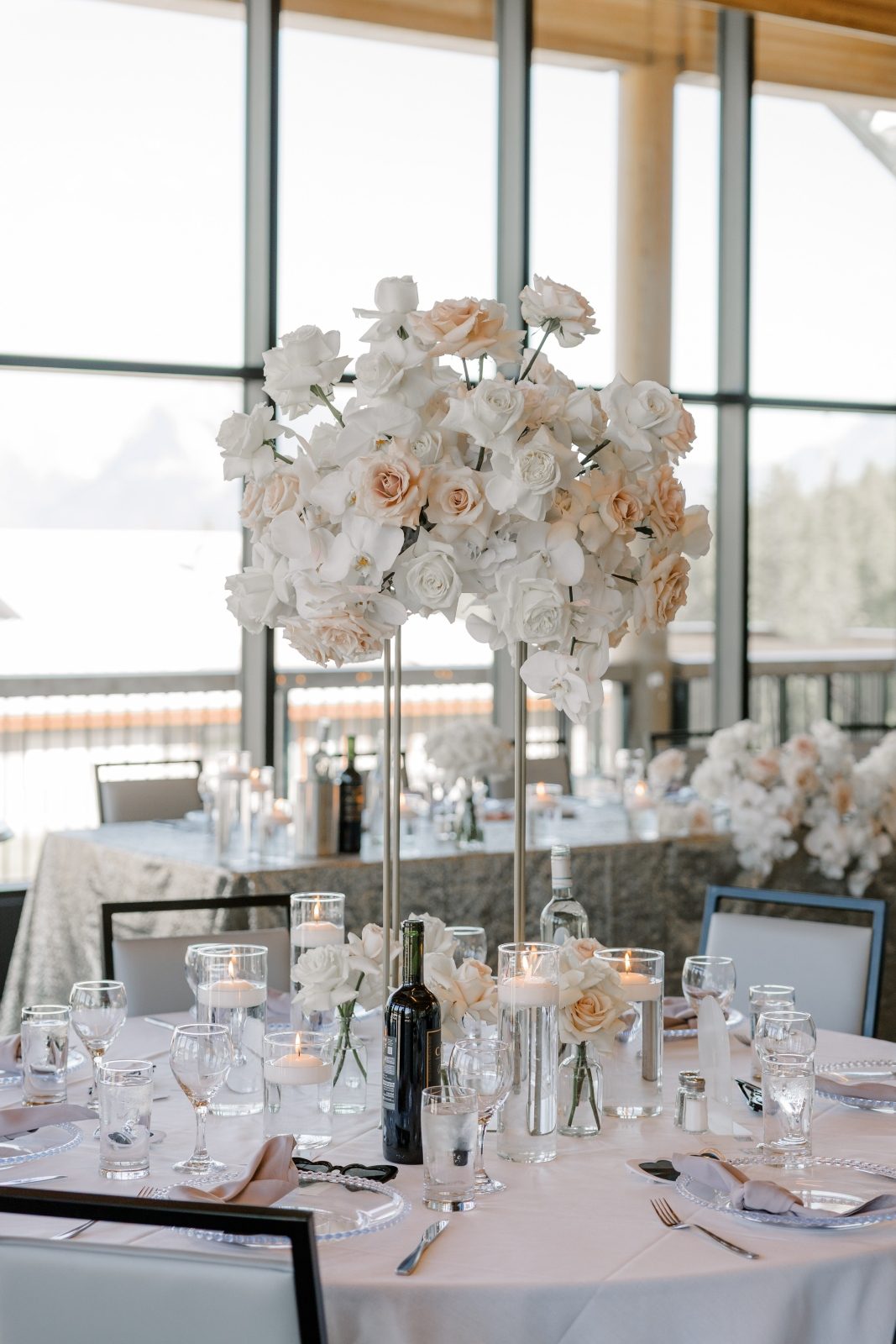 Stunning luxury beautiful wedding tall centerpiece designed on a gold harlow stand with white roses, white hydrangea, blush roses and phalaenopsis orchids with bud vases at the base of the stand at The Vista wedding venue