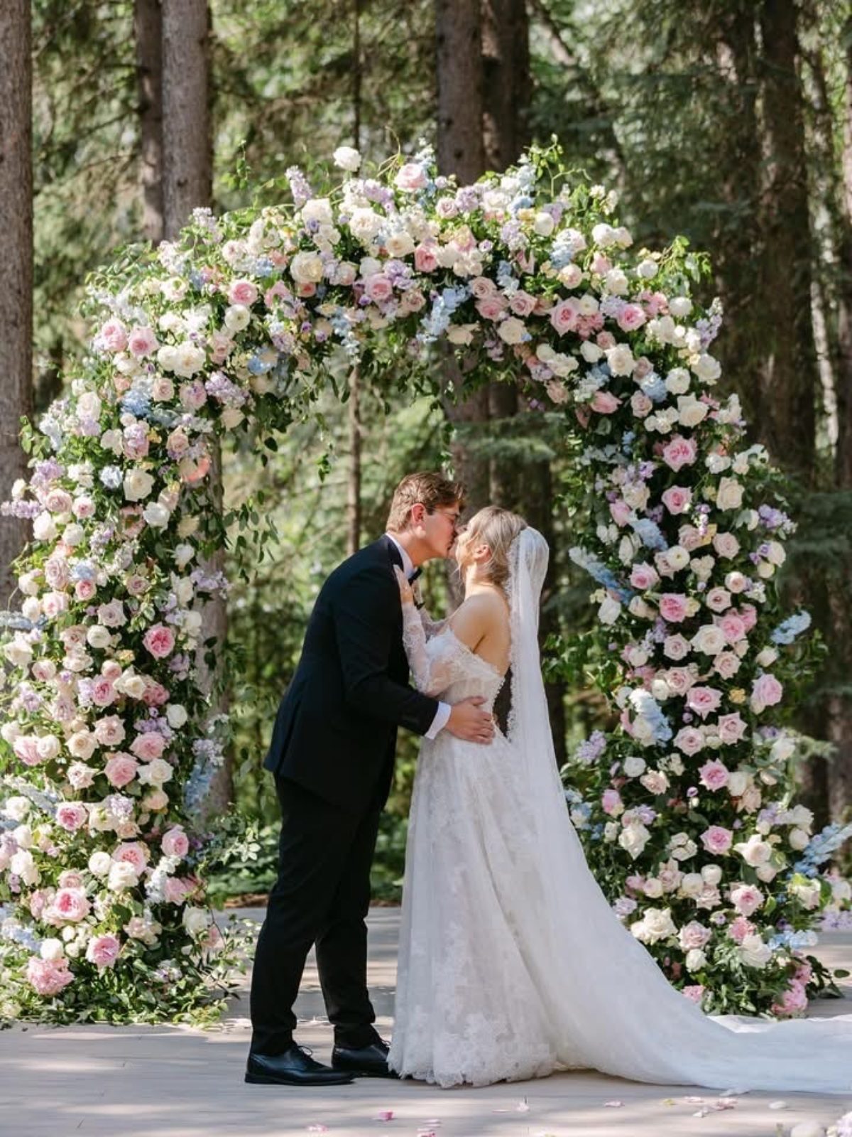 Grand luxury wedding ceremony with archway floral installation with garden roses in pastel tones of blush, pink, pale blue and lavender, light purple and bride and groom with bouquet at Archway Manor
