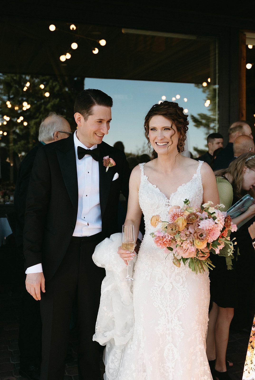 Beautiful Bride with her bouquet on a at a wedding reception designed with summer pastel flowers in peach, coral and yellow tones including dahlia, phlox, lisianthus, and butterfly ranunculus