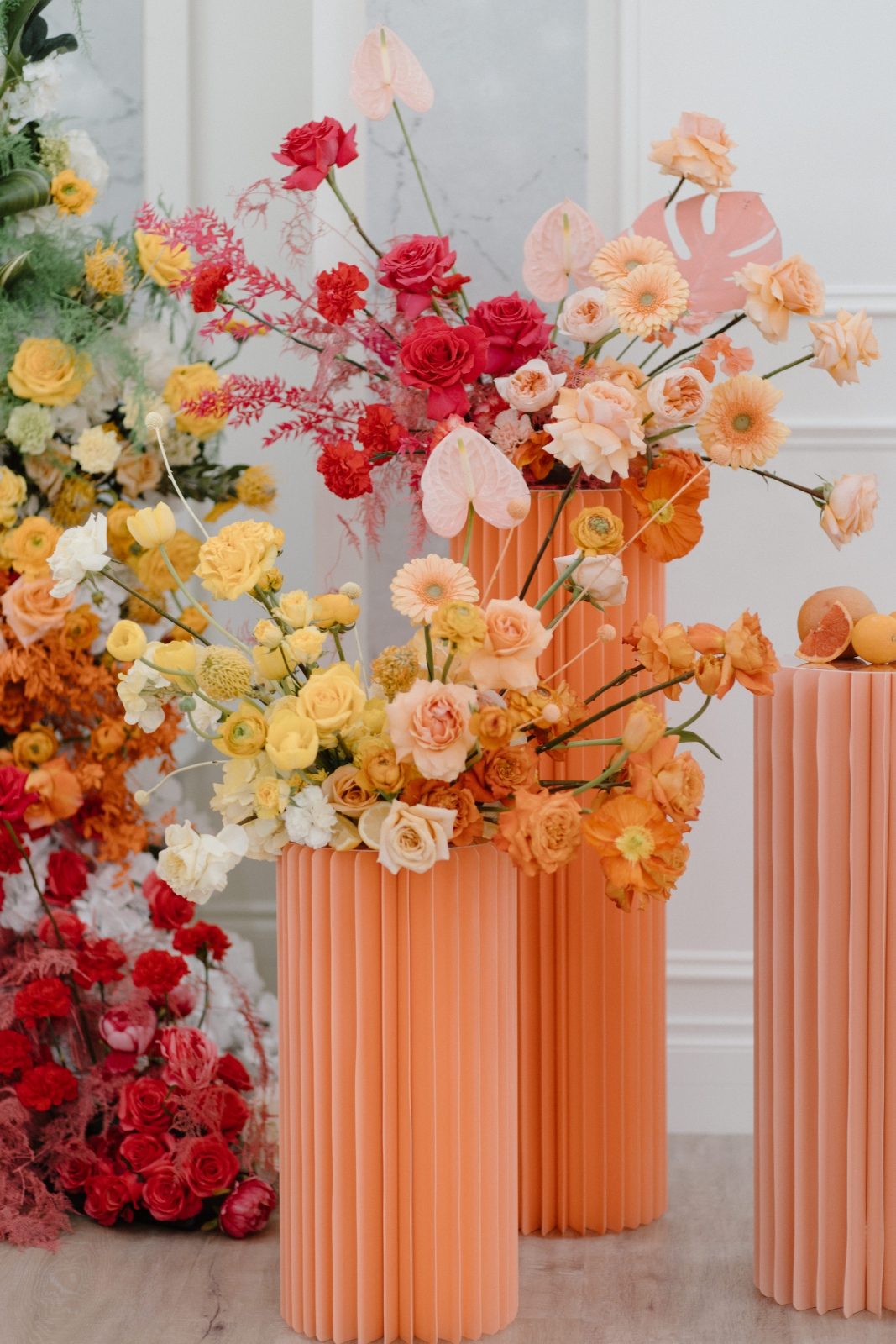Colorbocked wedding pillar arrangements in bright citrus tones of green, orange, yellow, pink and coral