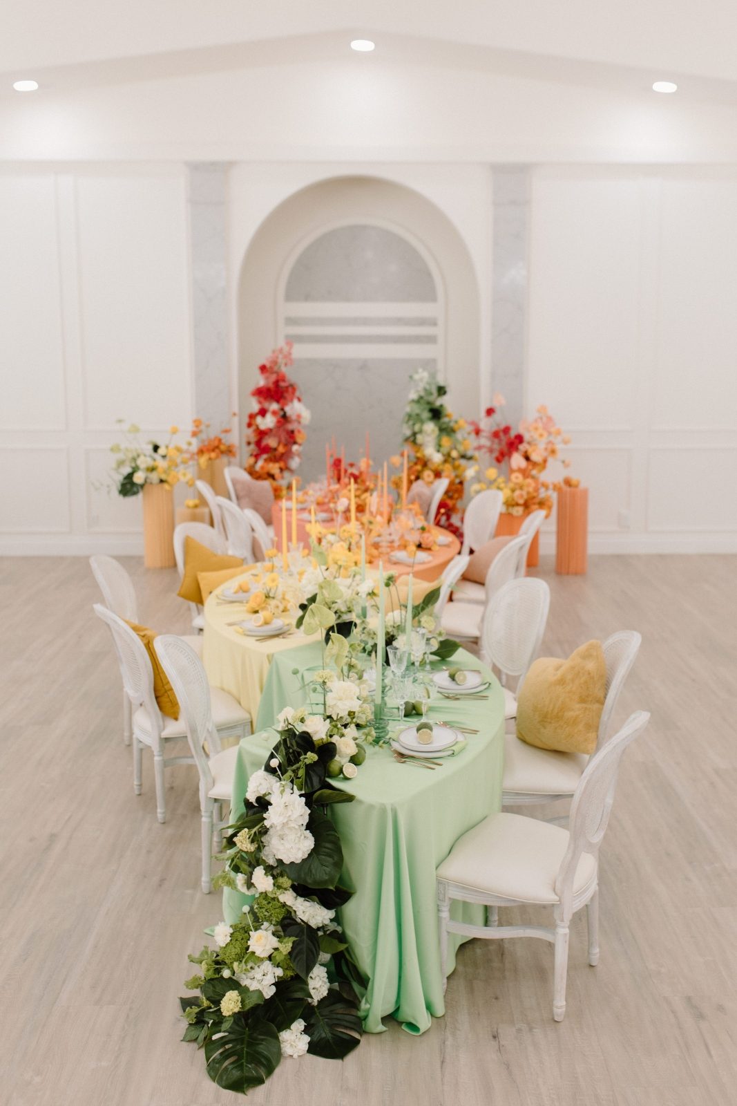 Colorbocked long serpentine table wedding flowers in bright citrus tones of green, orange, yellow, pink and coral with a table waterfall and pillar arrangements