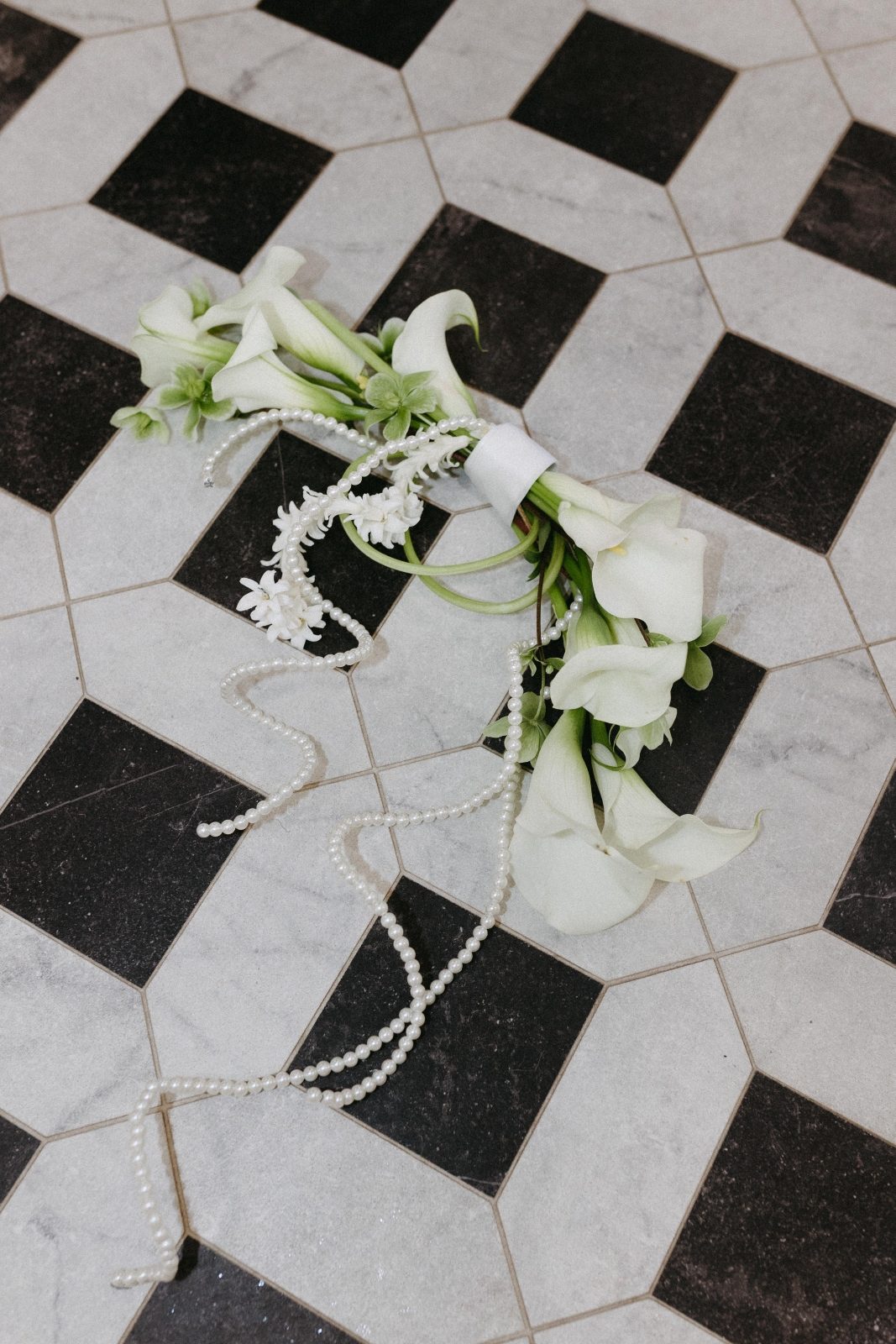 Modern bridal bouquet designed with white calla lilies, hyacinth blooms and pearls