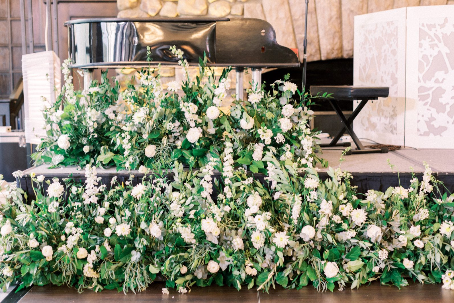 Piano Flowers Luxury green and white stage florals lining piano platform with lush greenery and white blooms.