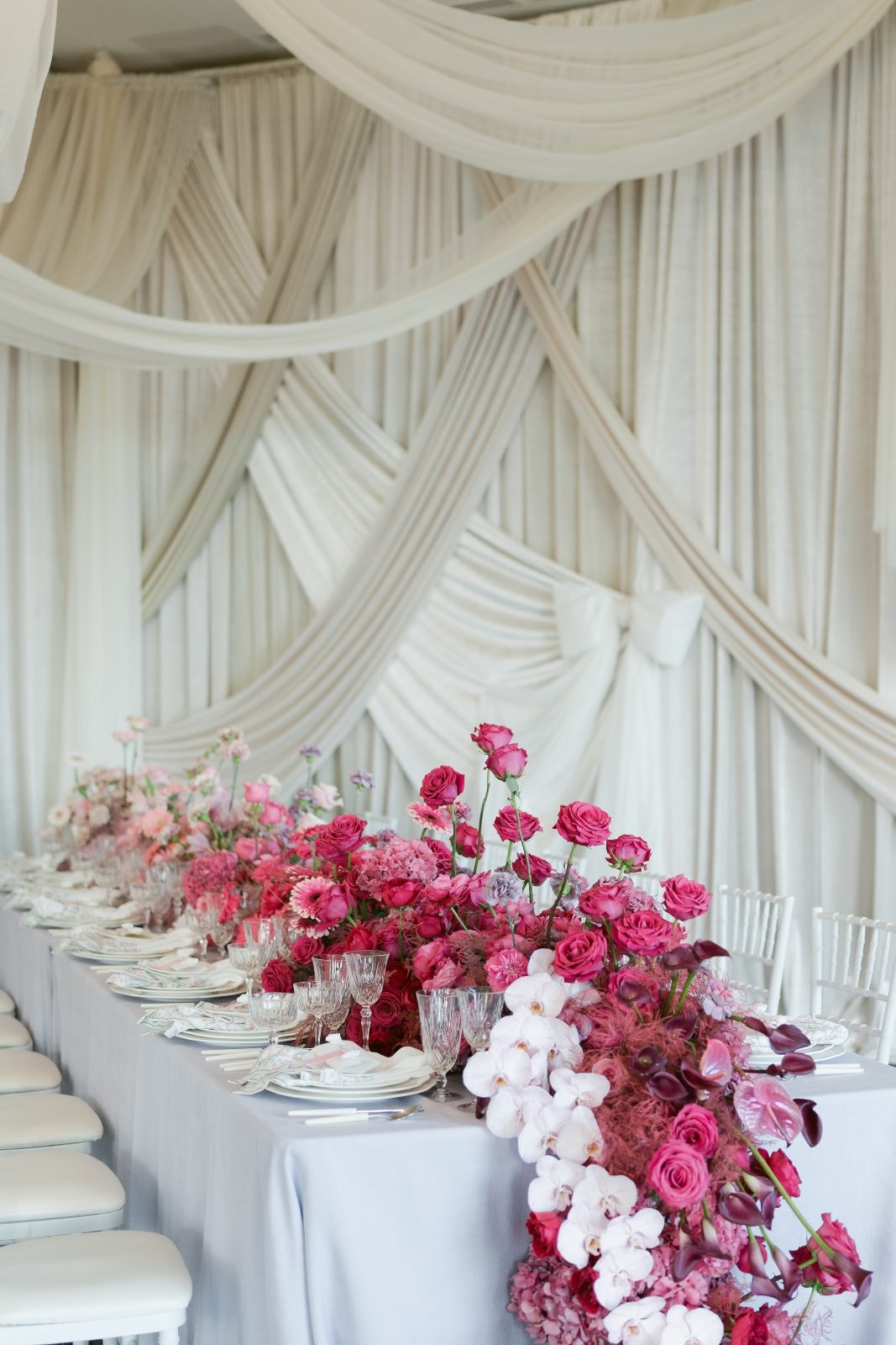 Pink ombre luxury long table centerpiece with modern white draping and Phalaenopsis orchids