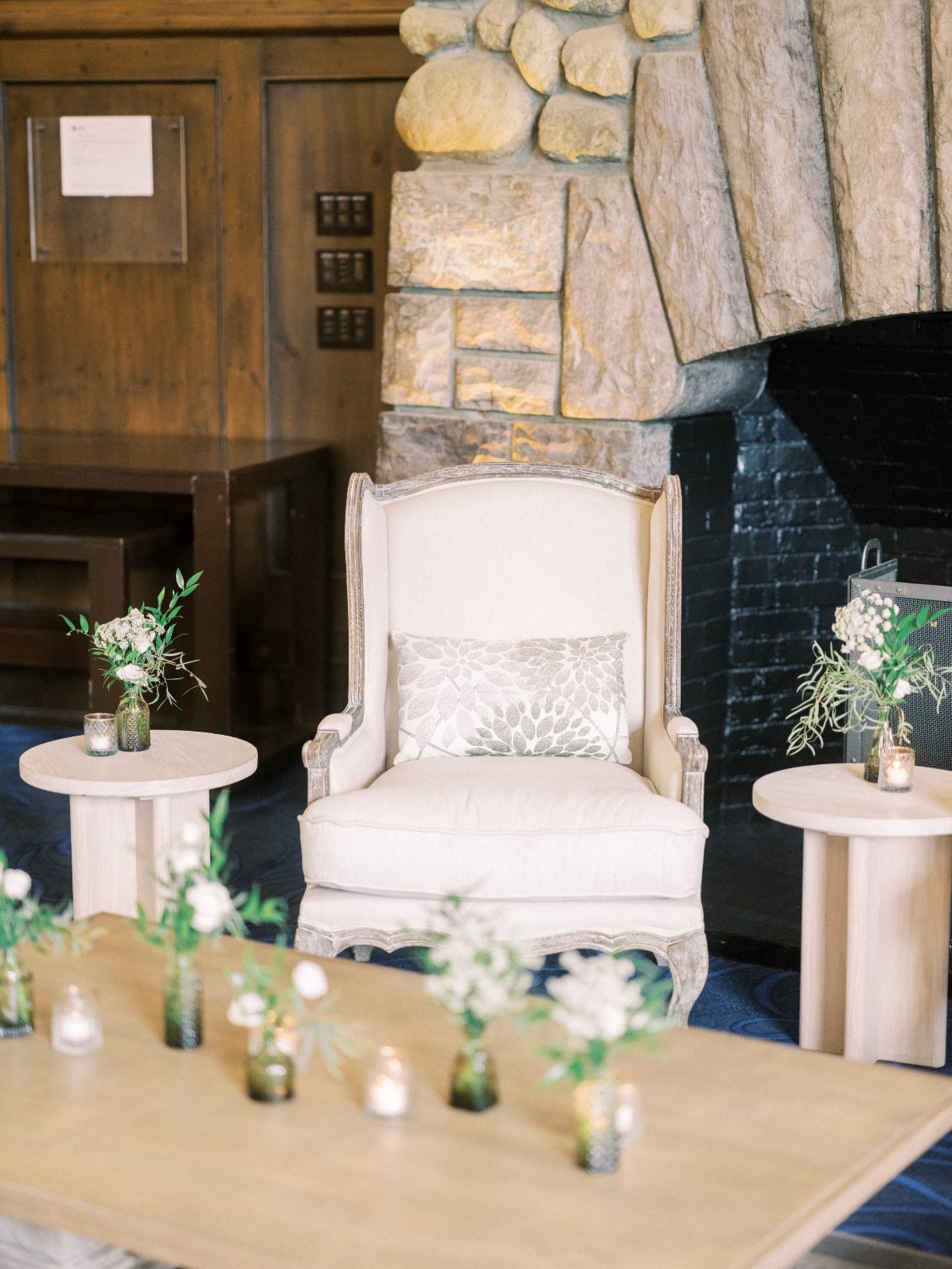 Seating Area Neutral lounge vignette with upholstered armchair, stone fireplace, bud vases and soft candlelight accents.