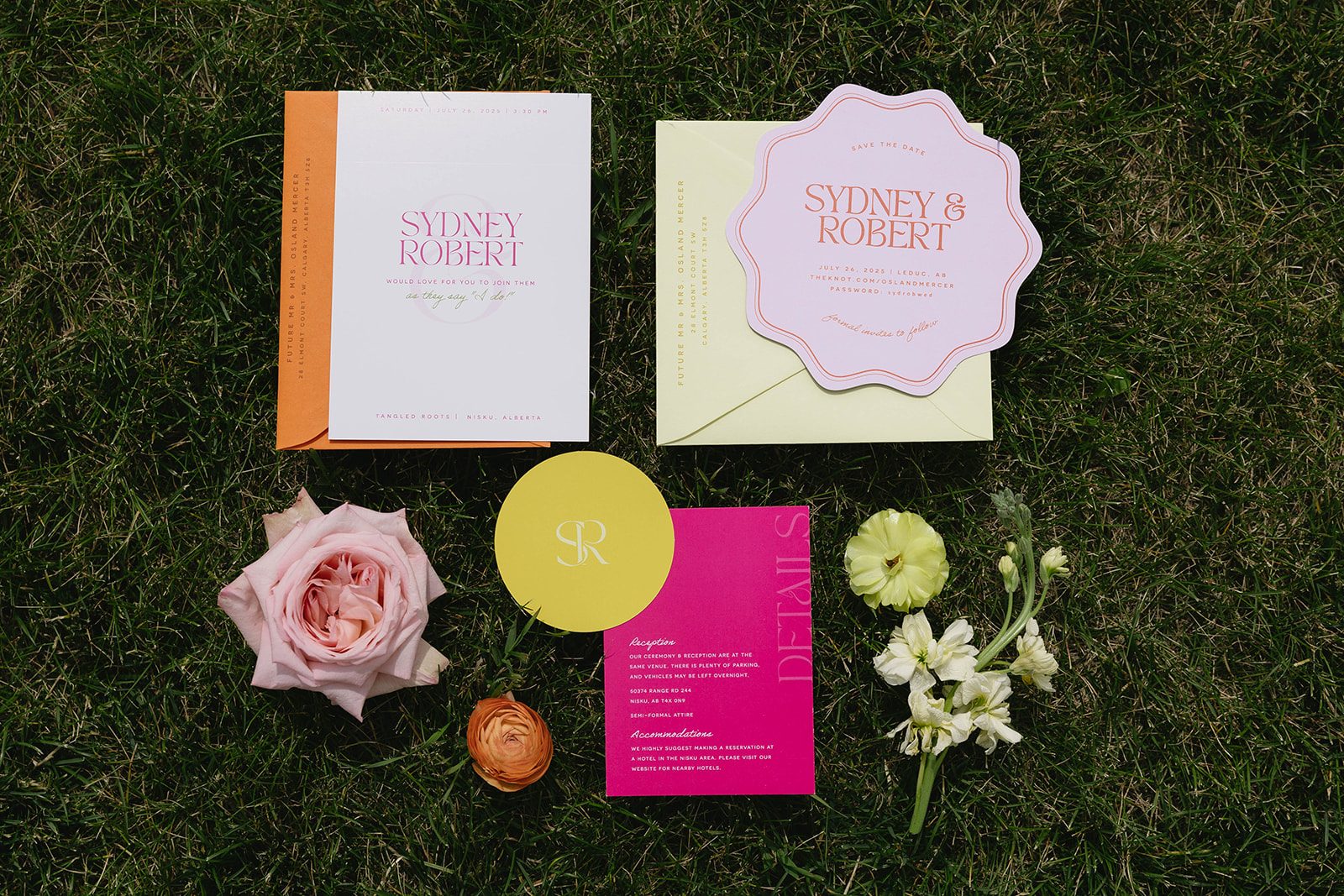 Colourful pastel garden wedding flatlay featuring modern Hartlee Designs stationery, garden rose, ranunculus, butterfly ranunculus and stock displayed in the grass.