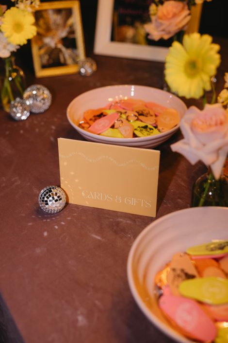 Some of the accents for a pastel garden wedding reception guestbook/gift table featuring mini disco balls and pastel floral arrangements.