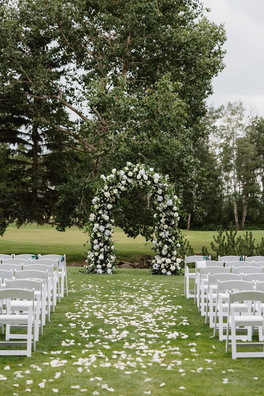 Cassidy + Adon Stunning solid floral arch full of white flowers and lush greenery, featuring roses, dahlias, ranunculus, eucalyptus and Italian ruscus.
