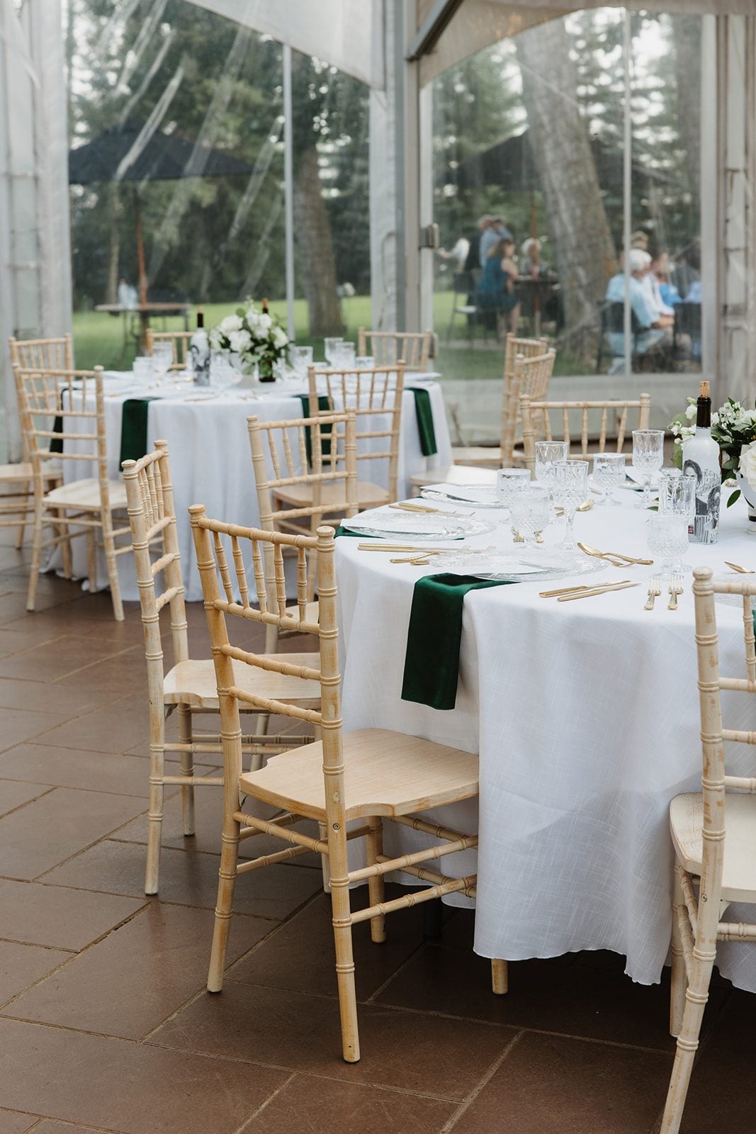 Cassidy + Adon Reception set up at Hilltop Wedding Center with ivory chairs, white tablecloths, green napkins, green and green and white centrepieces.