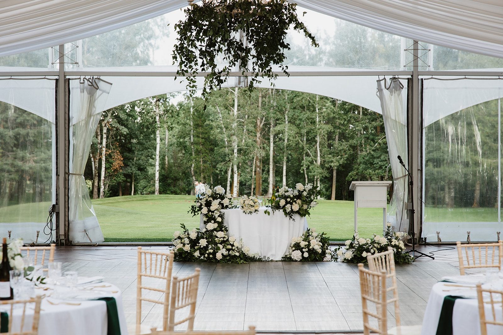 Cassidy + Adon Stunning green and white wedding reception at Hilltop, featuring a sweetheart table for the happy couple adorned with green and white floral designs and greenery chandeliers.