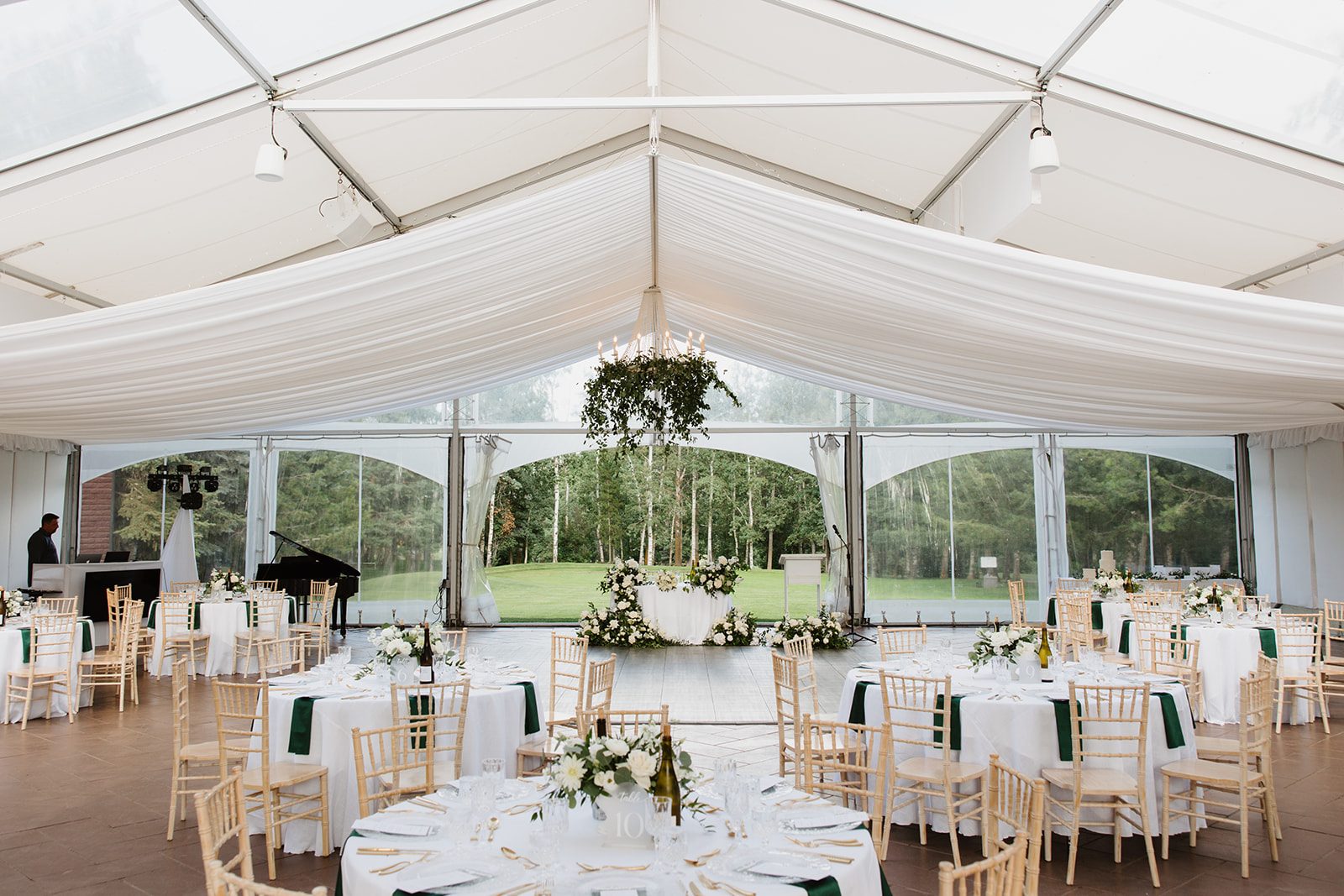 Cassidy + Adon Green and white wedding reception set up at Hilltop Wedding Center with hanging greenery chandeliers, white tables with green and white centrepieces and a sweetheart table adorned with green and white arrangements.