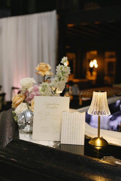 At the bar of the reception at Tangled Roots, a menu card sits in front of a pastel arrangement accented by a couple small disco balls.