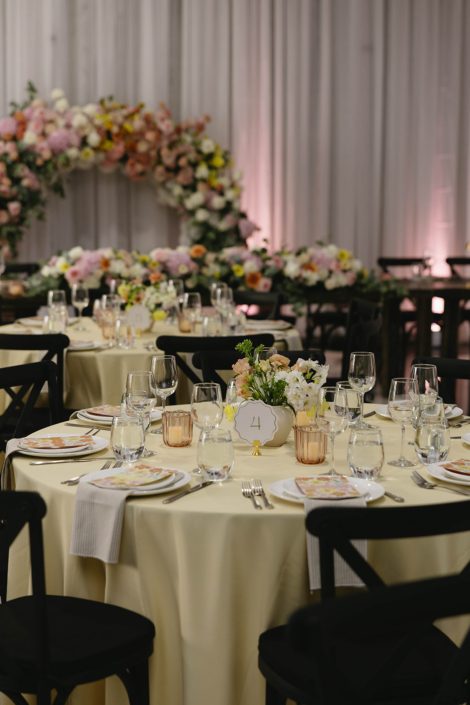 Round guest tables featured a pastel, loose garden inspired centrepiece on yellow table linens, with floral stationery and amber tea light votives.