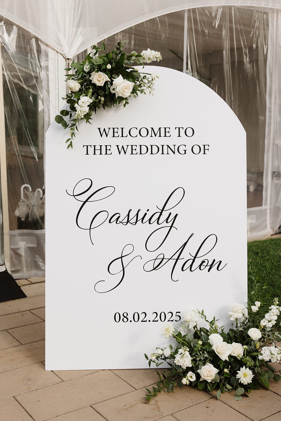 Cassidy + Adon Welcome sign for green and white Hilltop Wedding Center wedding, accented with floral arrangements at both the top and the base.