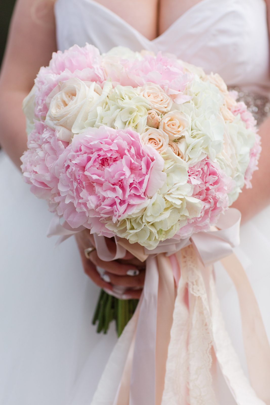 Romantic pastel pink peonies in a bridal bouquet with hydrangea, roses and spray roses.