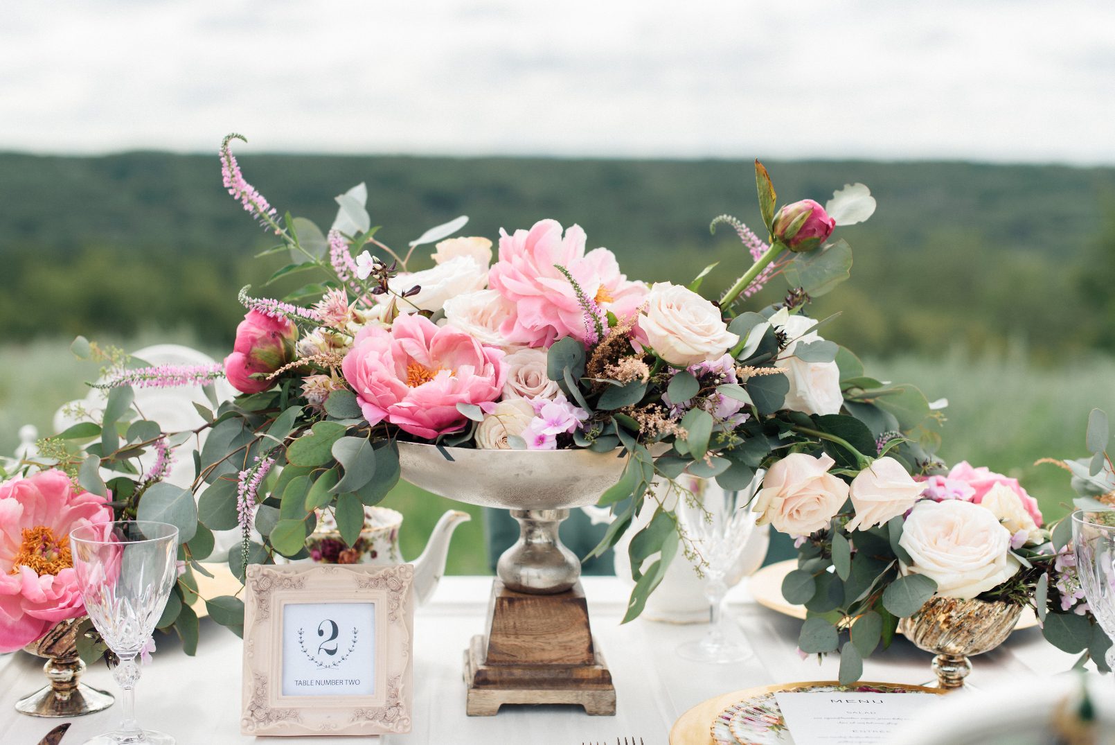 A styled photoshoot with a table scape with a stunning centrepiece featuring coral charm peonies as its focal point.