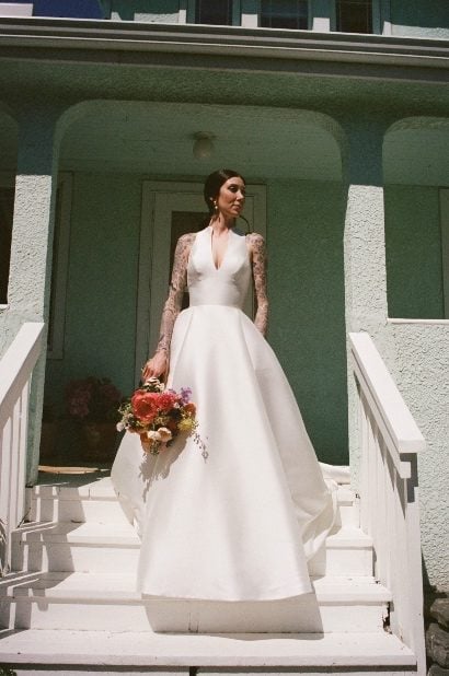 Bride with Colourful Bouquet with Peony The bride stands on the steps of a porch holding a colourful bouquet of garden inspired flowers like peonies, chamomile, poppies, sweet pea, ranunculus and roses.