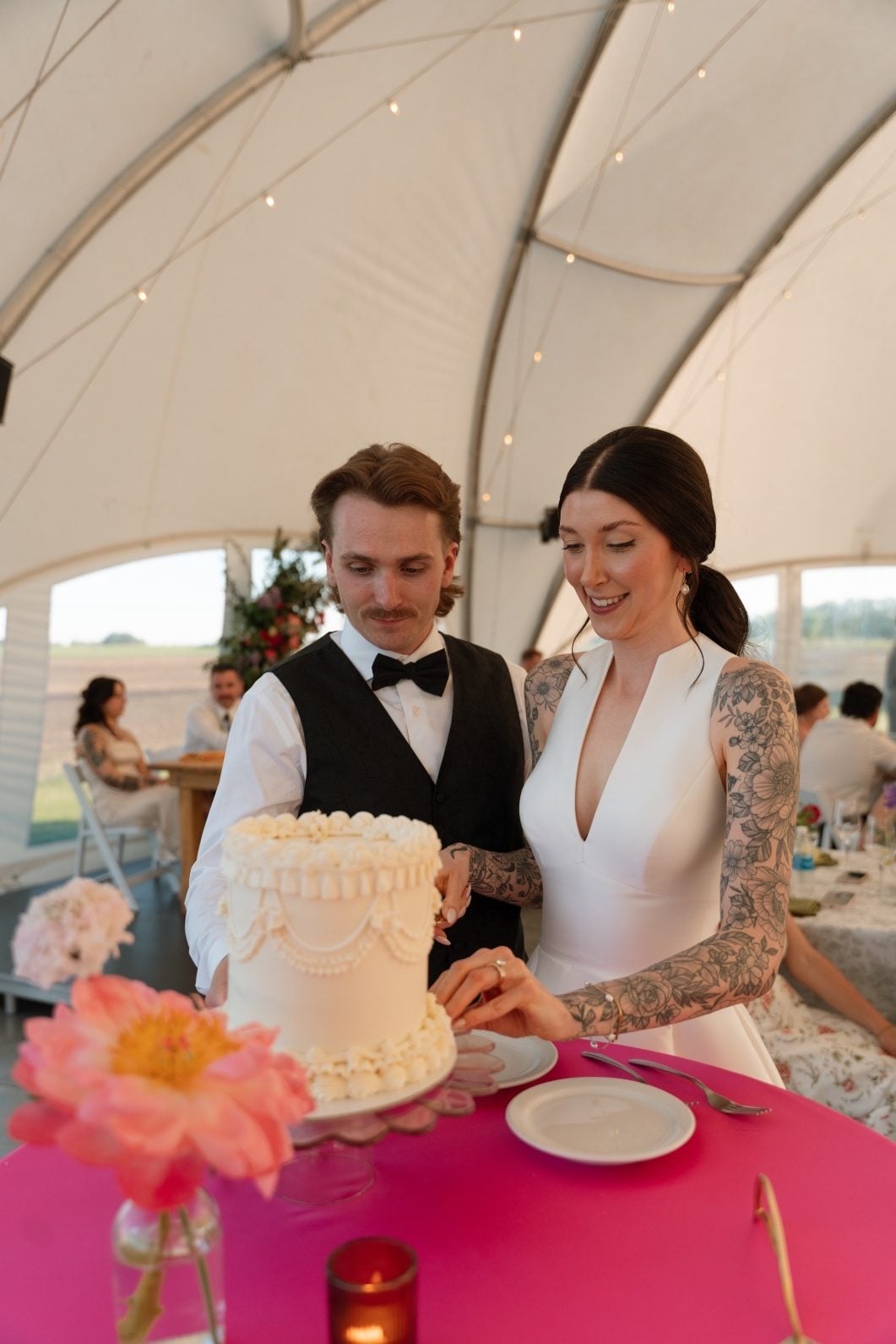 Calyx Couple Cutting Cake The bride and groom standing together to cut the wedding cake at their colourful wedding reception.